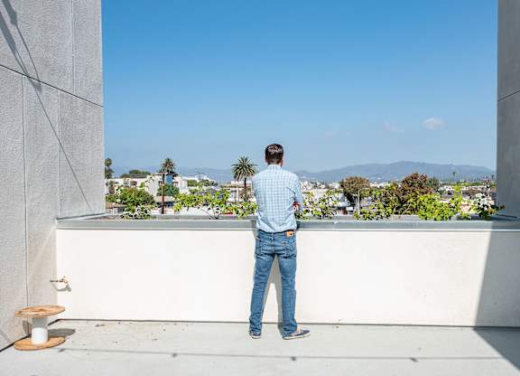 A man stands on a balcony looking out at the view.