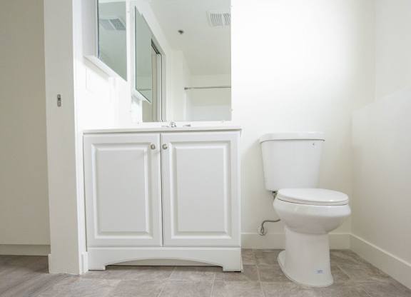 A white toilet sits next to a white cabinet in a bathroom.