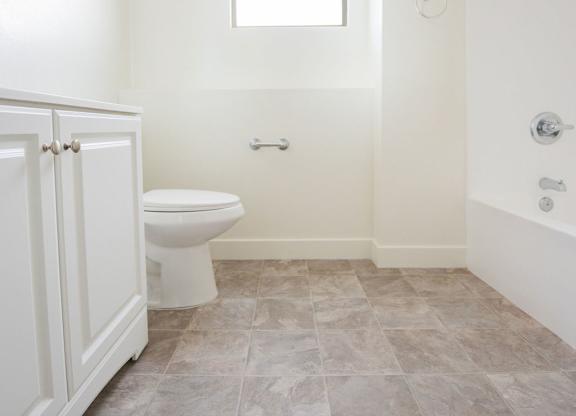 A bathroom with a toilet, sink, and tiled floor.