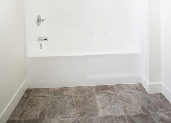 A white bathroom with a tiled floor and a shower.