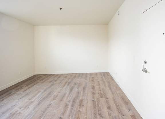 A room with wooden flooring and white walls.