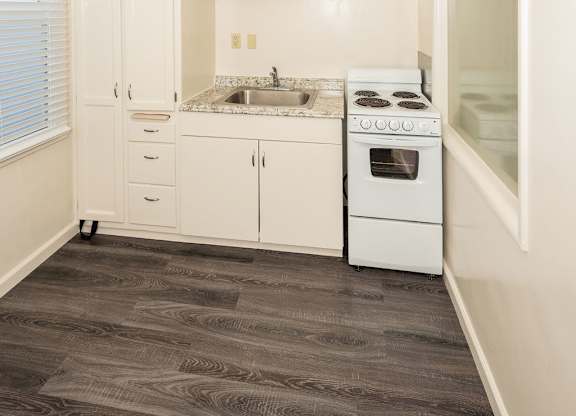 A kitchen with white cabinets and a vinyl floor.