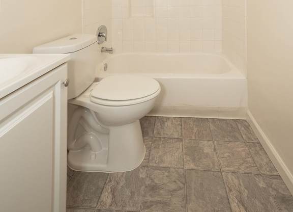 A white toilet sits in a bathroom next to a bathtub.