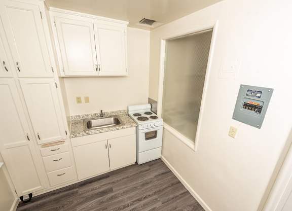 A small kitchen with white cabinets and a stove top oven.