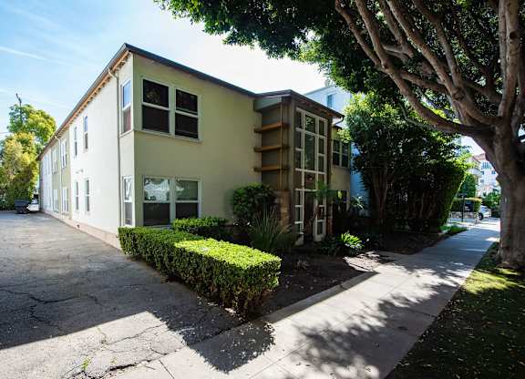 A two-story building with a green hedge in front.