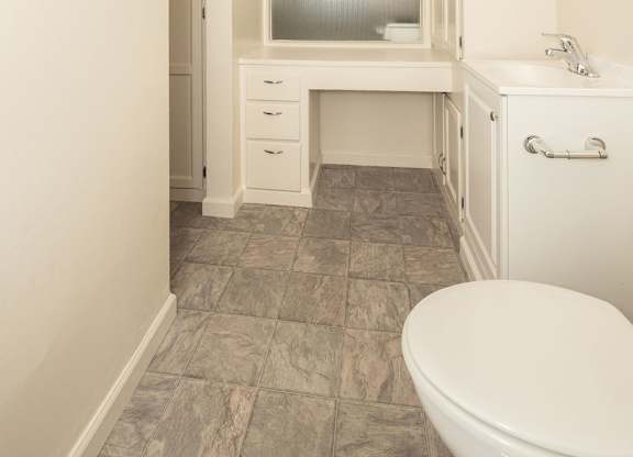 A white bathroom with a toilet, sink, and vanity.