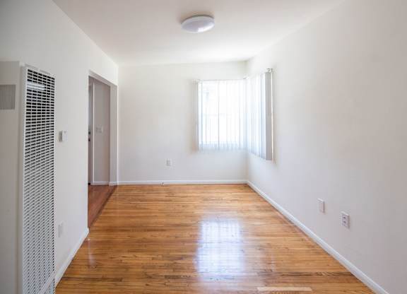 A room with wooden floors and a window with blinds.