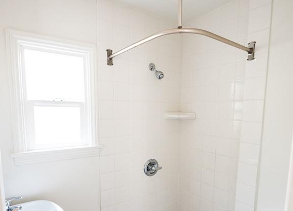 A white bathroom with a toilet, sink, and shower.