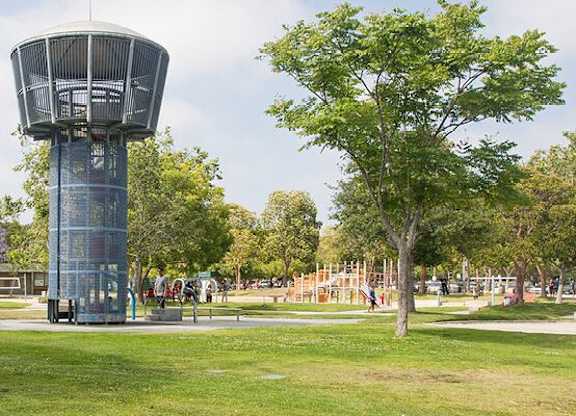 A large water tower in a park with trees and a playground.
