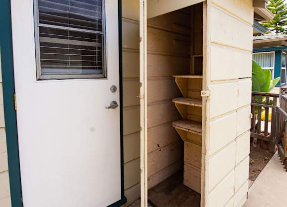 A small white door with a green frame is open to a storage space.