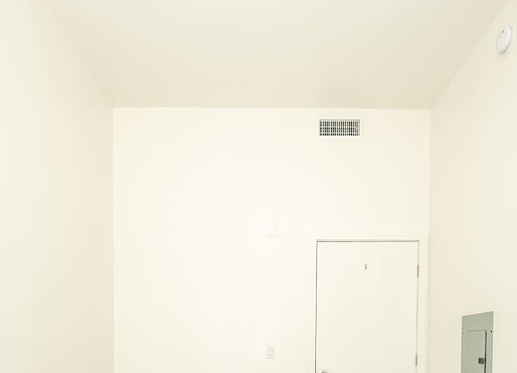 A room with a white door and a light switch on the wall.