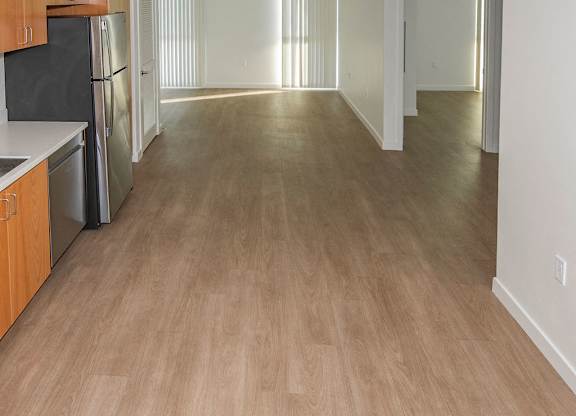 Sample 2 Bedroom Unit: A kitchen with vinyl floors and a black fridge.