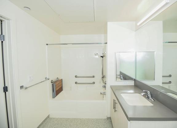 A white bathroom with a sink, mirror, and shower.