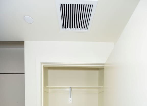 A white closet with a white door and a white shelf.
