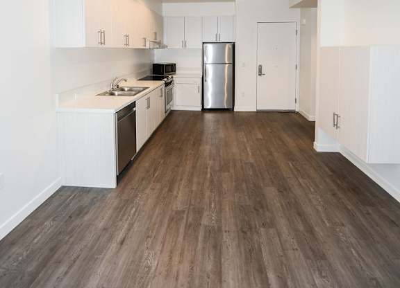 A kitchen with white cabinets and a wooden floor.