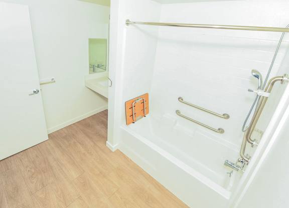 Sample 2 Bed Accessible Unit: A white bathroom with a walk in shower and a towel rack.