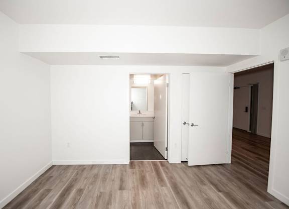 A room with a white door and a wooden floor.