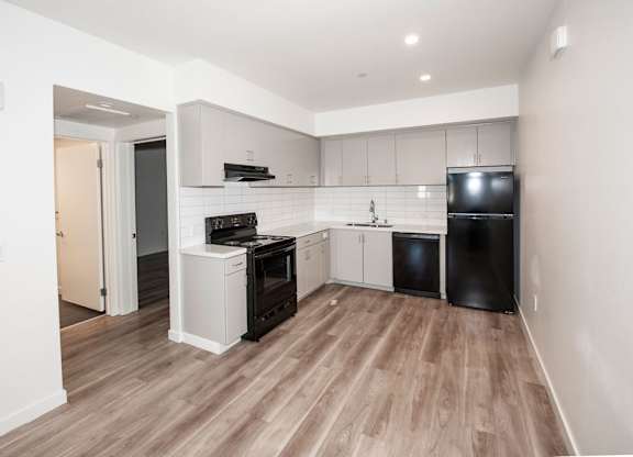 A kitchen with black appliances and white cabinetry.