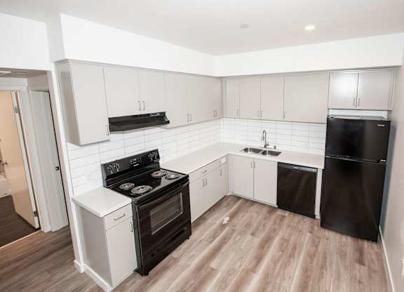 A kitchen with black appliances and white cabinets.