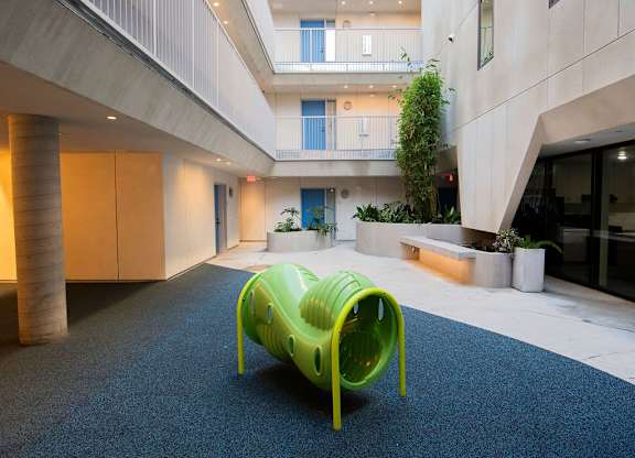 A bright green plastic chair sits on a carpeted floor in a modern building.