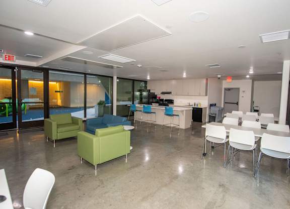 A room with white chairs and tables and a green couch.