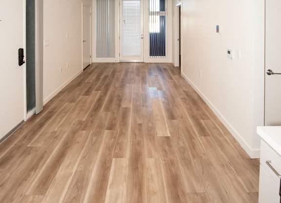 A long hallway with wooden floors and white walls.