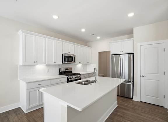 A white kitchen with a refrigerator, microwave, and oven.