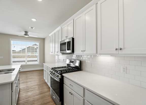 A kitchen with white cabinets and a black stove top.