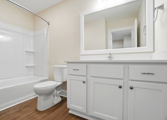A white toilet sits in a bathroom next to a white cabinet.