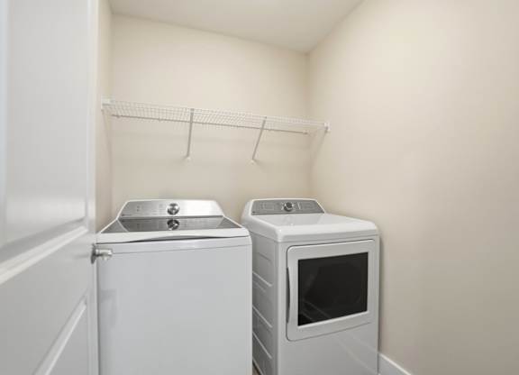 A white washing machine and microwave in a small laundry room.