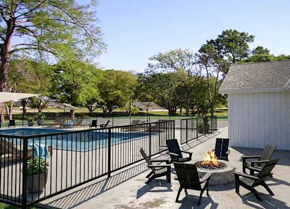 A pool with a fence and chairs around it.