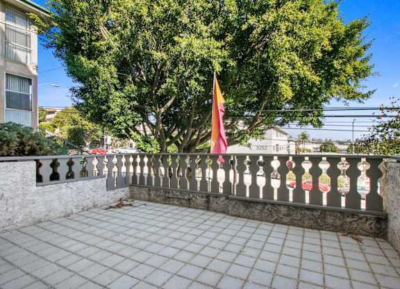 A balcony with a flag and a tree in the background.