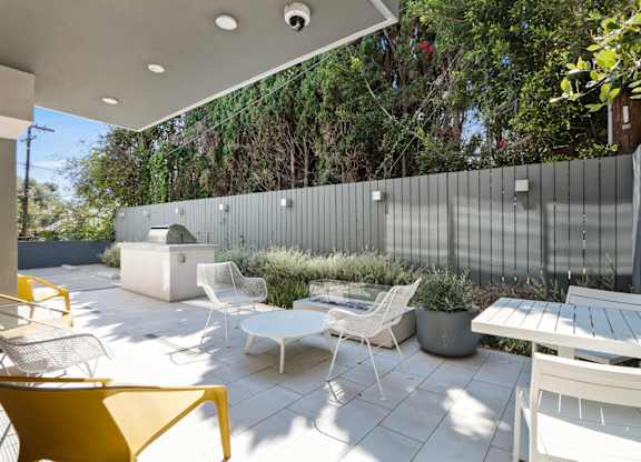 a patio with a table and chairs and a privacy fence at The Aster, Los Angeles, 90024