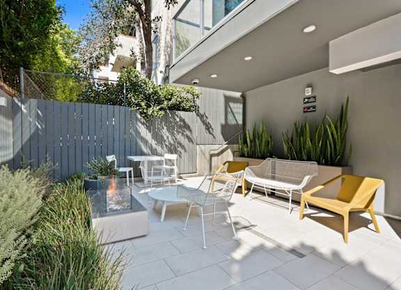 a patio with chairs and tables and a blue fence at The Aster, Los Angeles