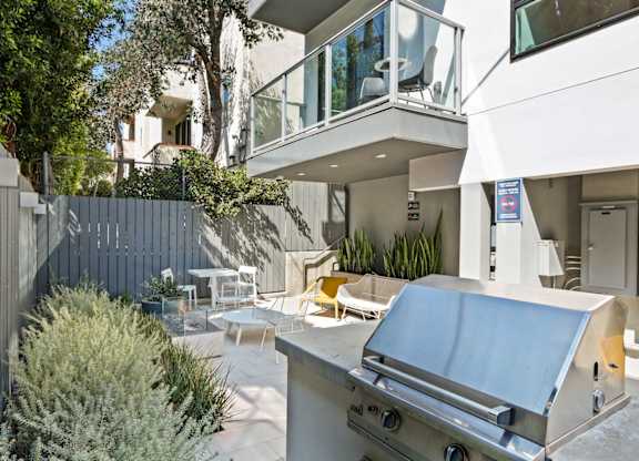 a backyard with a barbecue grill and a patio with tables and chairs at The Aster, Los Angeles