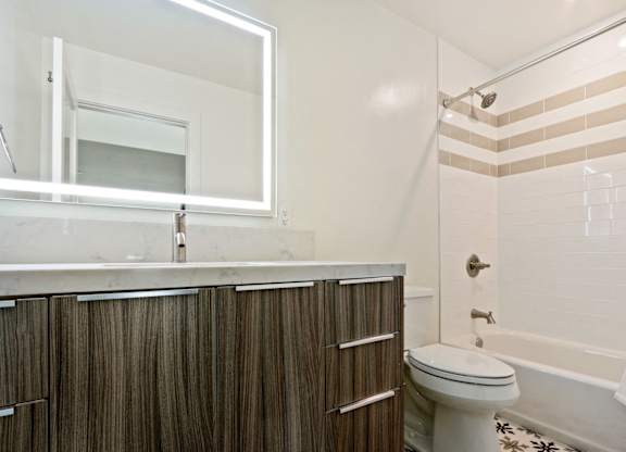 Bathroom with single vanity, quartz countertops, LED mirrored lights, wood cabinets, hot tub and shower combo