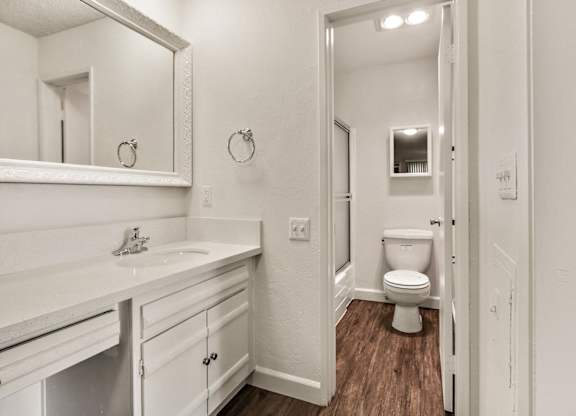 Single vanity area with white quartz countertops, white cabinets bathroom on the right