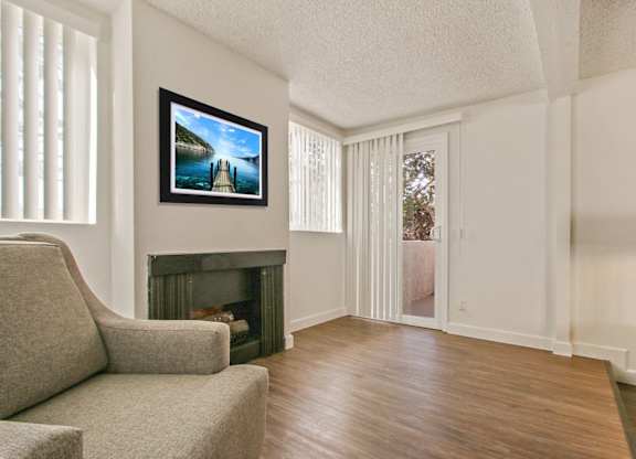 Living room with cozy fireplace, wood inspired floors, balcony or patio on the right, vertical blinds