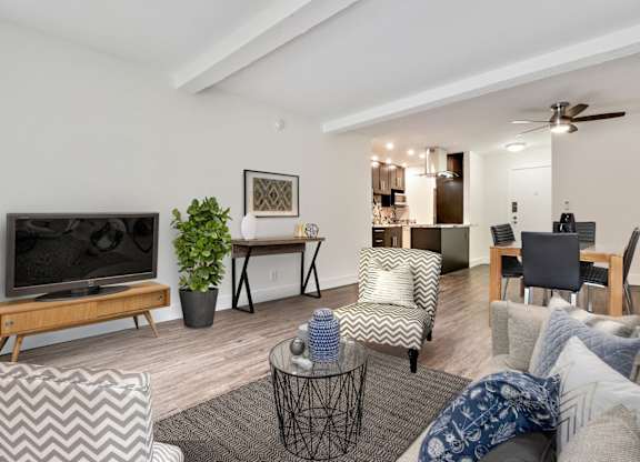 Gorgeous interior of a one bedroom, dining are with ceiling fan, kitchen with breakfast bar, living room with woos inspired flooring throughout the unit
