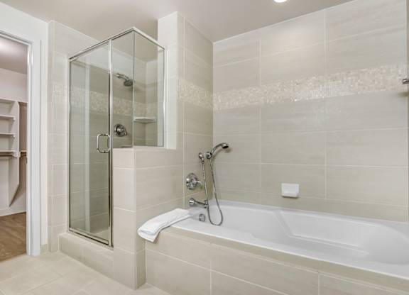 A modern bathroom with a glass shower enclosure and a white bathtub.at Wilshire Margot, Los Angeles, 90024 