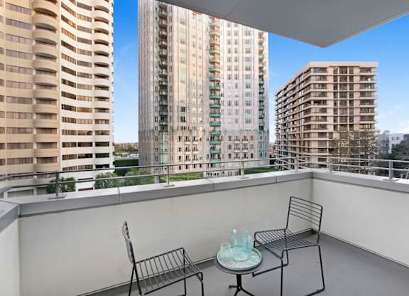 A balcony with a table and two chairs overlooks a cityscape.at Wilshire Margot, Los Angeles California 