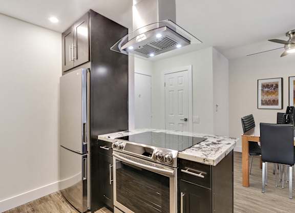 Kitchen with Stainless steel appliances, including electric range over range hood, granite countertops ,dark brown kitchen cabinets, wood style floors
