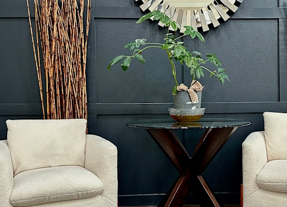 a living room with two chairs and a table with a plant