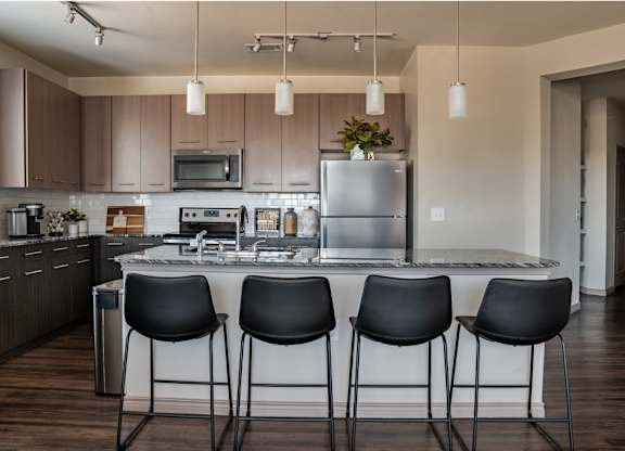 a kitchen with a large island with four chairs around it