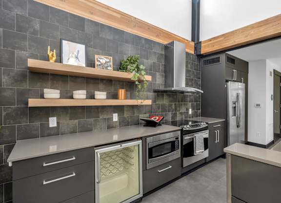 Modern kitchen with dark tile backsplash and wood shelving at The Lyric Apartments, Seattle, 98102
