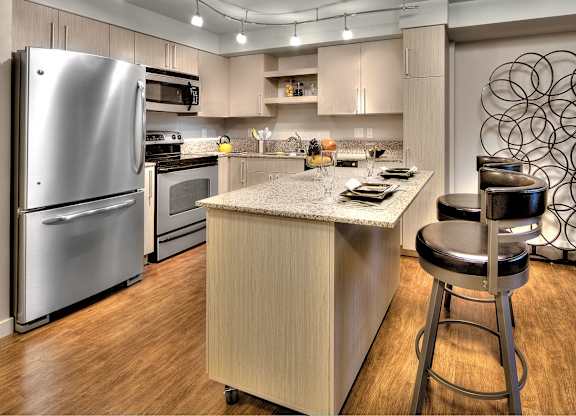 Modern kitchen with island and bar seating at The Lyric Apartments, Seattle, WA