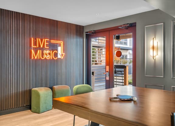 Game room with ping pong table and live music neon sign at The Lyric Apartments, Seattle, WA 98102