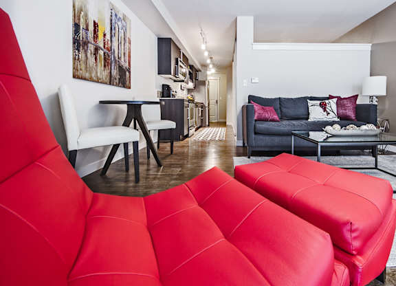 Open concept living room with red accent chair at The Lyric Apartments, Seattle, 98102