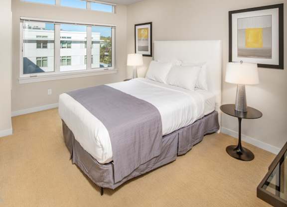 Bedroom with white upholstered headboard and natural light at The Lyric Apartments, Seattle, WA