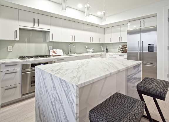 a large kitchen with a marble counter top and stainless steel appliances